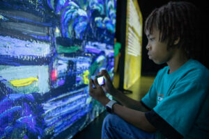 Student using camera at the Beyond Van Gogh Exhibit